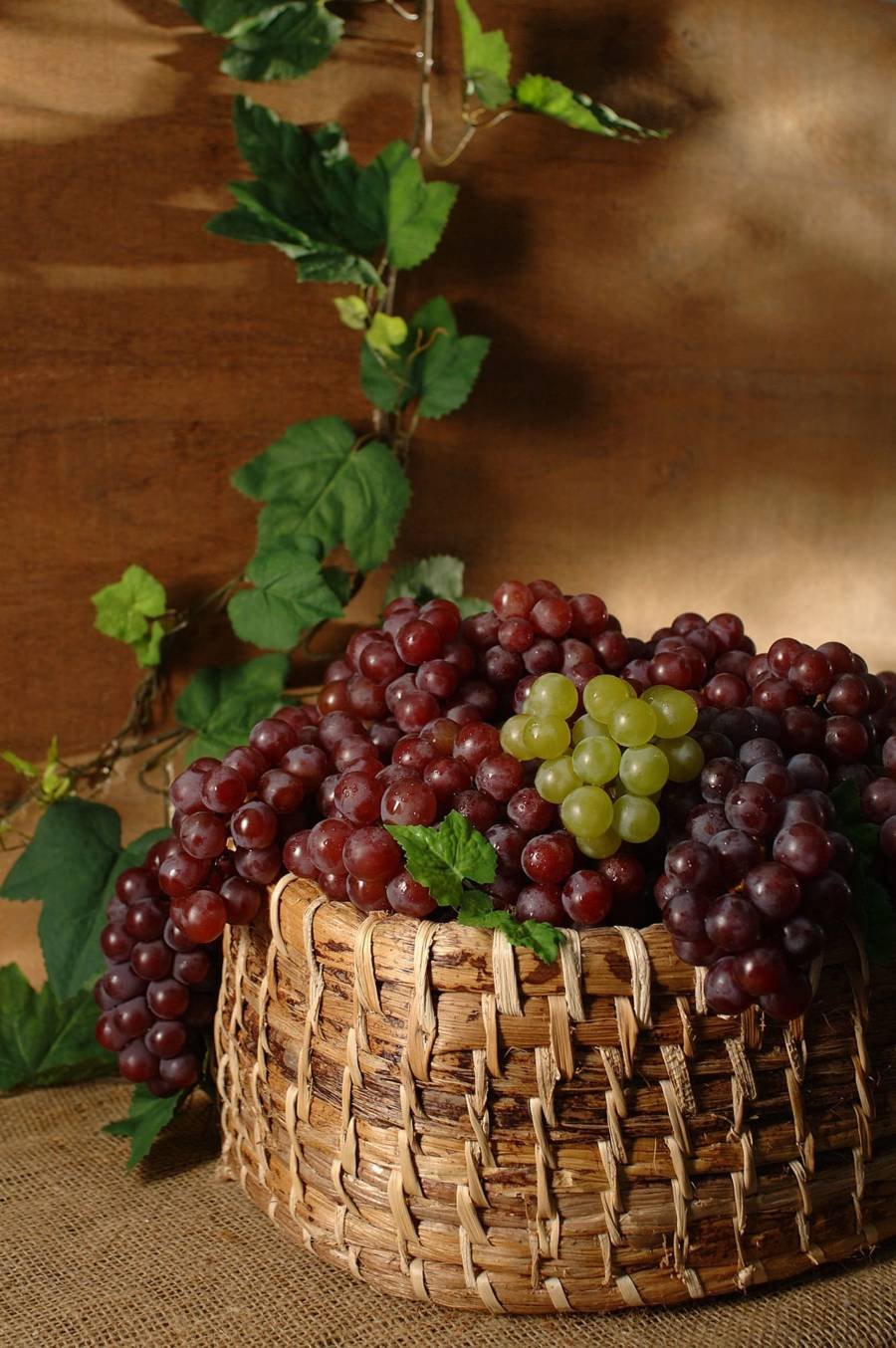 cesta com uvas, fundo em madeira com folhas