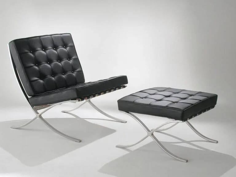 poltrona e banqueta com etofado em couro preto trabalhados com botões também pretos, pernas dos estofados com design moderno de cor prata
