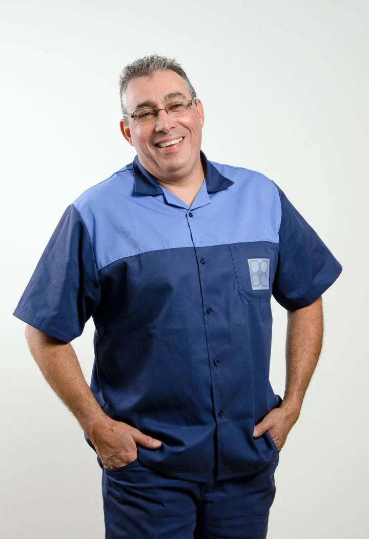 funcionário, sorrindo, com uniforme da empresa, mãos no bolso, fundo branco