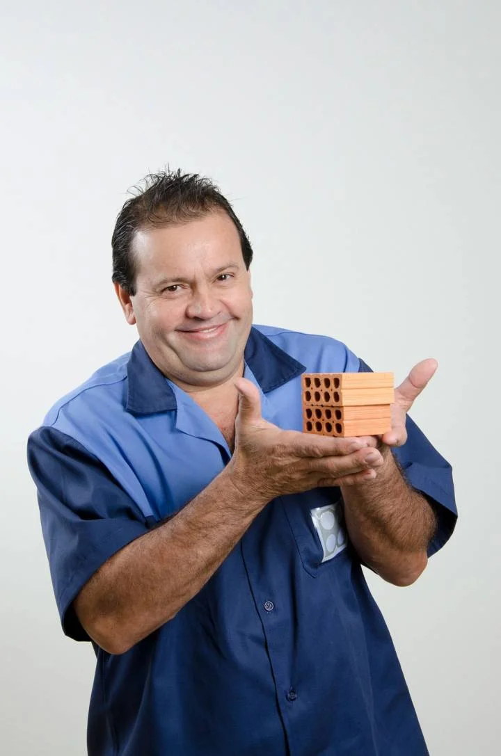 funcionário uniformizado segurando blocos de cerâmica em miniatura