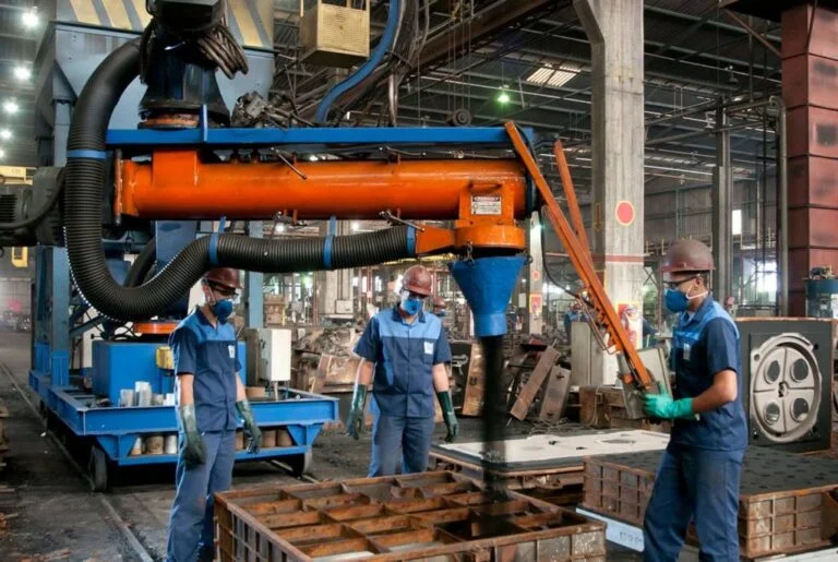 ambiente de fábrica, com 3 funcionários uniformizados em ação