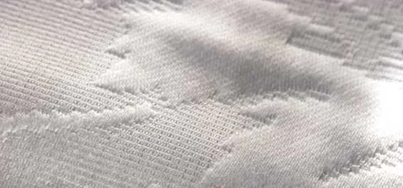 tecido branco com desenhos bordados com linha branca