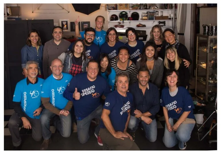 grupo de pessoas posando para foto em clima animado, trajando camiseta institucional